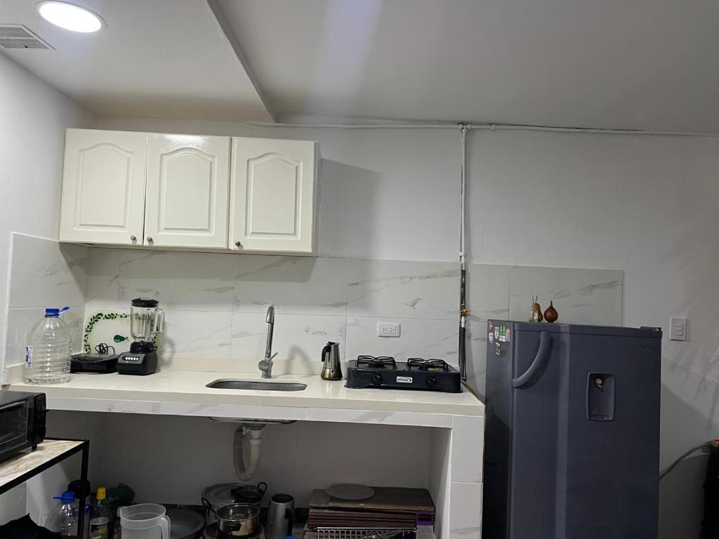 cocina con armarios blancos y nevera azul en Casa Linda, en Armenia