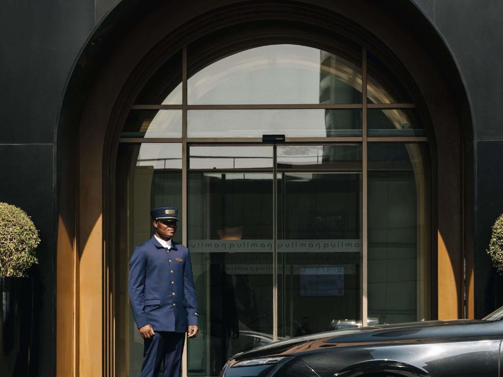 a man in uniform standing in front of a building at Pullman Dubai Jumeirah Lakes Towers in Dubai