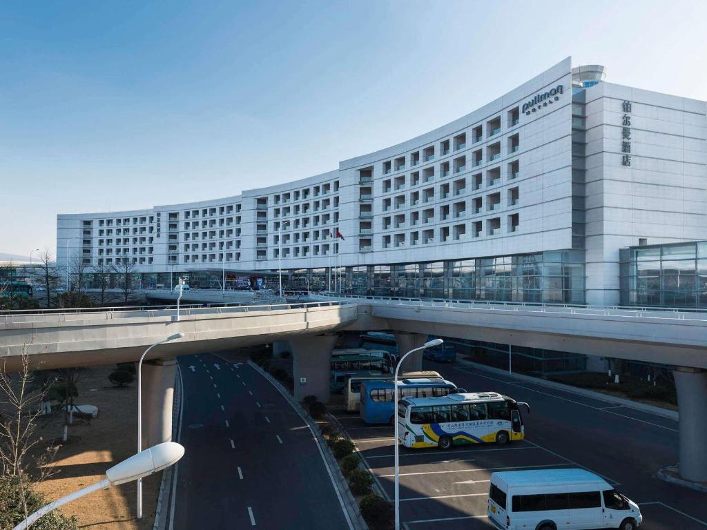 a large white building with a bridge over a highway at Pullman Nanjing Lukou Airport in Nanjing