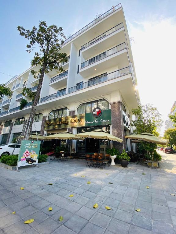 a large building with tables and umbrellas in front of it at Helen Halong Hotel in Ha Long