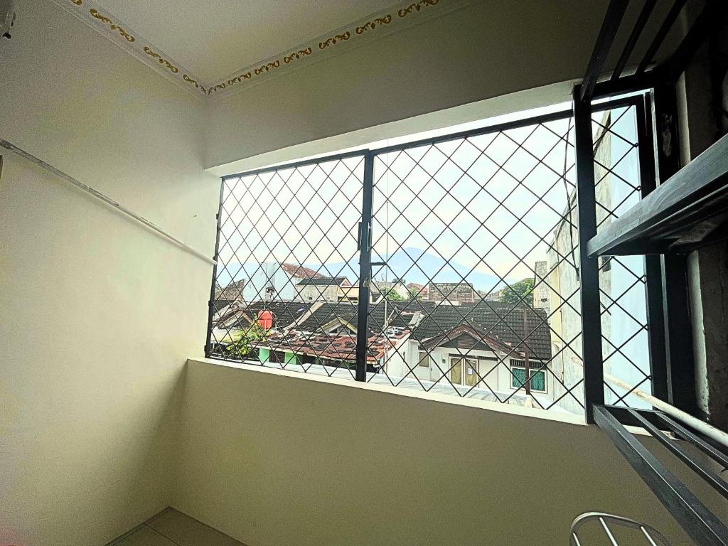 - une fenêtre dans une chambre avec vue sur une maison dans l'établissement SIJI Homestay Purwokerto, à Purwokerto