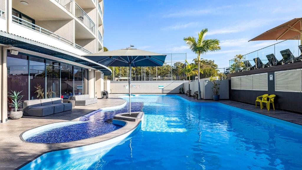 a swimming pool with an umbrella in a building at The Landmark- Top Level in Nelson Bay