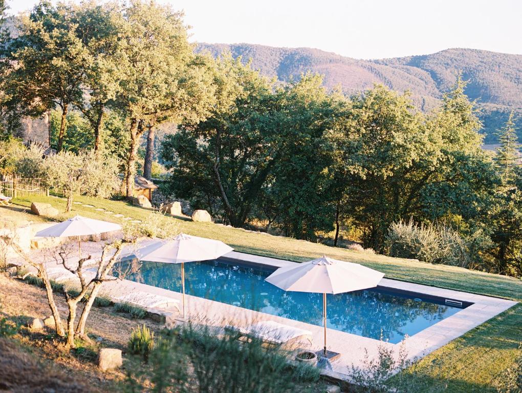 two umbrellas and a swimming pool with mountains in the background at Villa Montanare - romantic escape Tuscany in Cortona