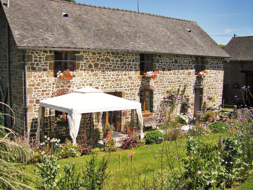 a stone house with a white table in the yard at La Cloue in Sainte-Marie-du-Bois