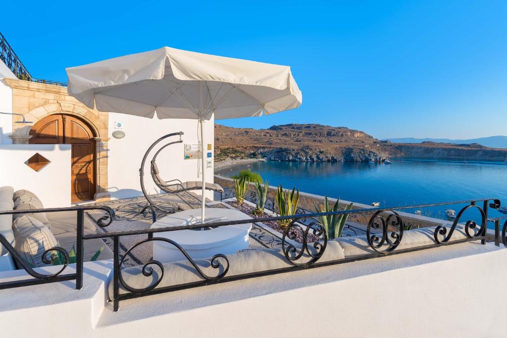 un patio con sombrilla y vistas al agua en Lindos Shore Boutique Villa with sea view, en Lindos