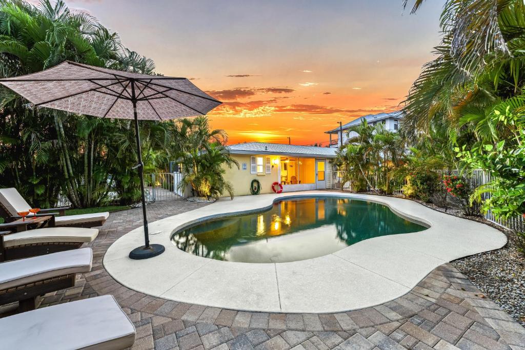 a pool with an umbrella and chairs and a house at The Solaster in Siesta Key