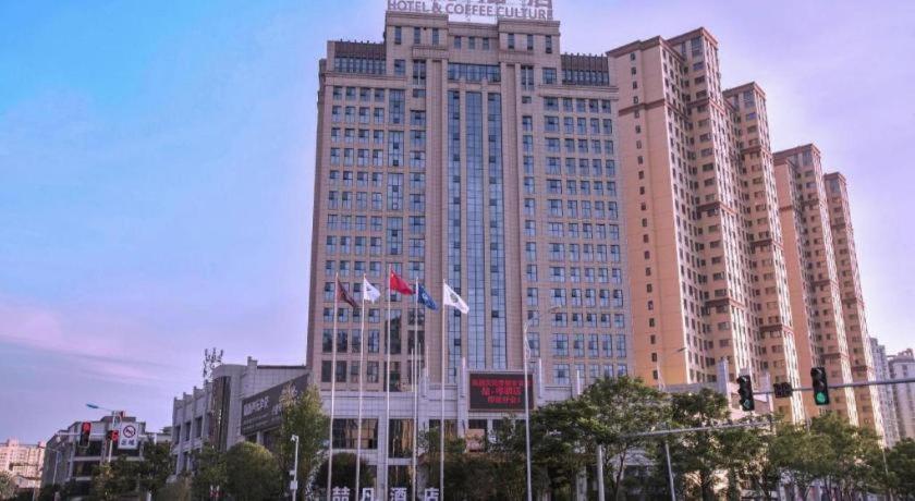 a large tall building with flags in front of it at James Joyce Coffetel· Changde Liuyehu in Changde