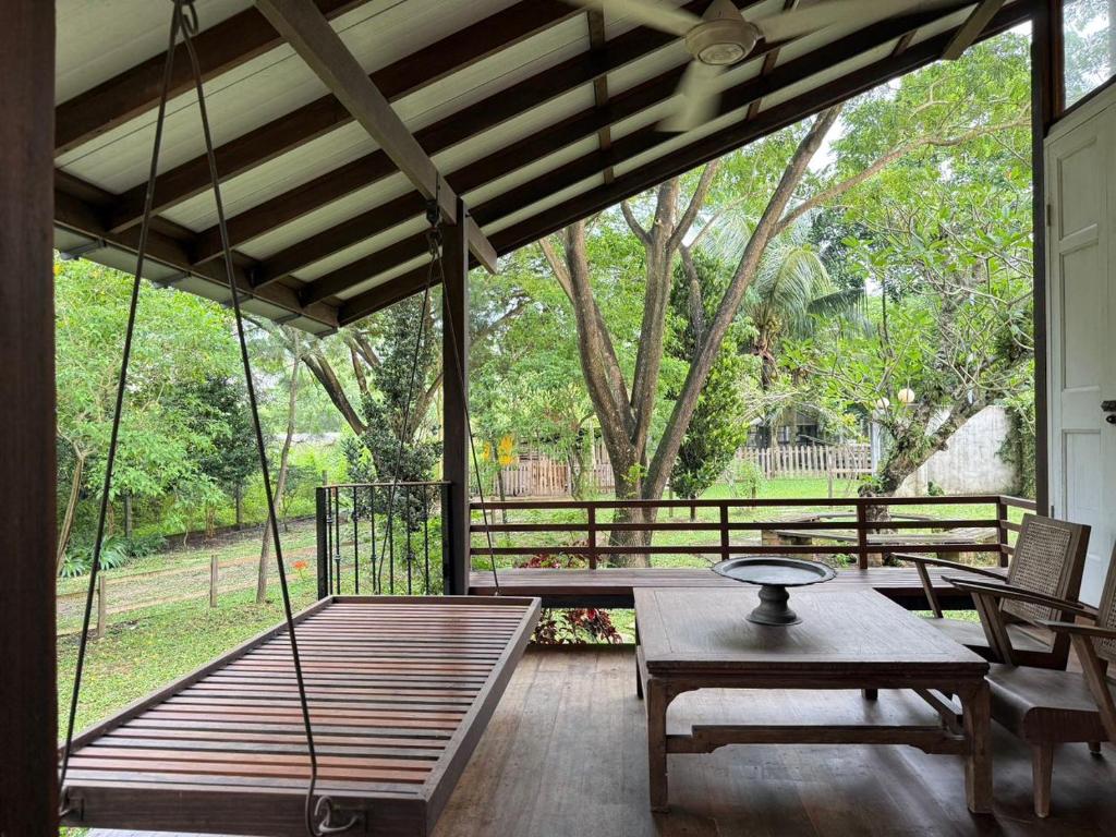 a screened in porch with a table and chairs at Rain Tree Country Home in Bukit Mertajam