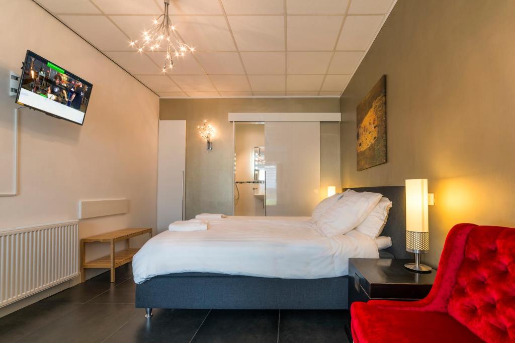 sypialnia z dużym łóżkiem i czerwonym krzesłem w obiekcie B&B Groene Meent w mieście Leerdam