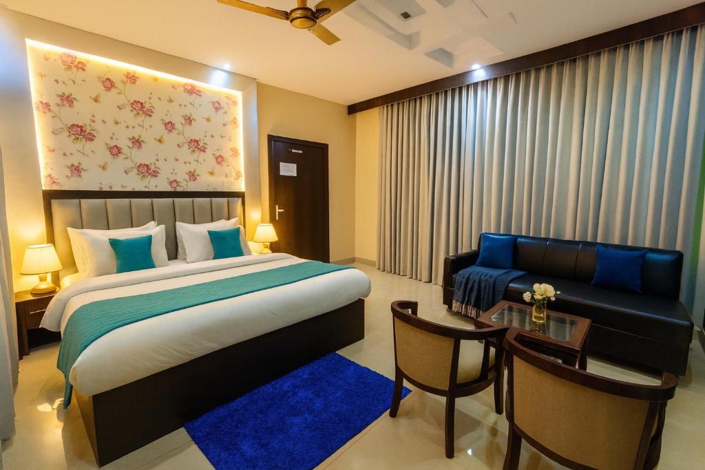 a bedroom with a bed and a chair and a couch at Hotel Ramawati, A Luxury Hotel & Resort, Haridwar in Haridwār