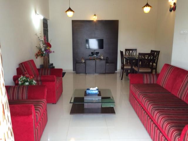 een woonkamer met rode banken en een tafel bij Kevlin Beach Apartment in Candolim