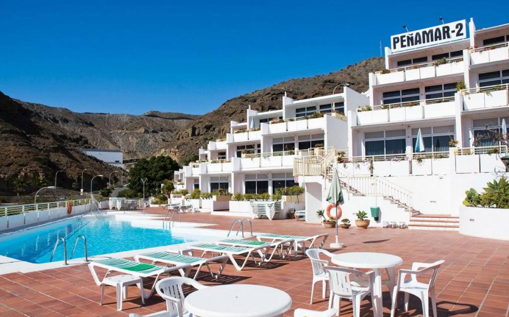 un hotel con mesas y sillas junto a una piscina en Peñamar Tour, en Puerto Rico de Gran Canaria