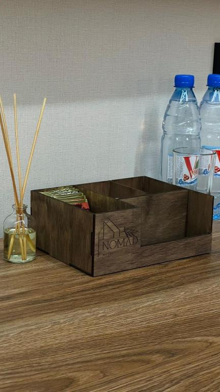drewniane pudełko na stole z butelkami wody w obiekcie NOMAD Self Check in Hotel w mieście Zhezdi