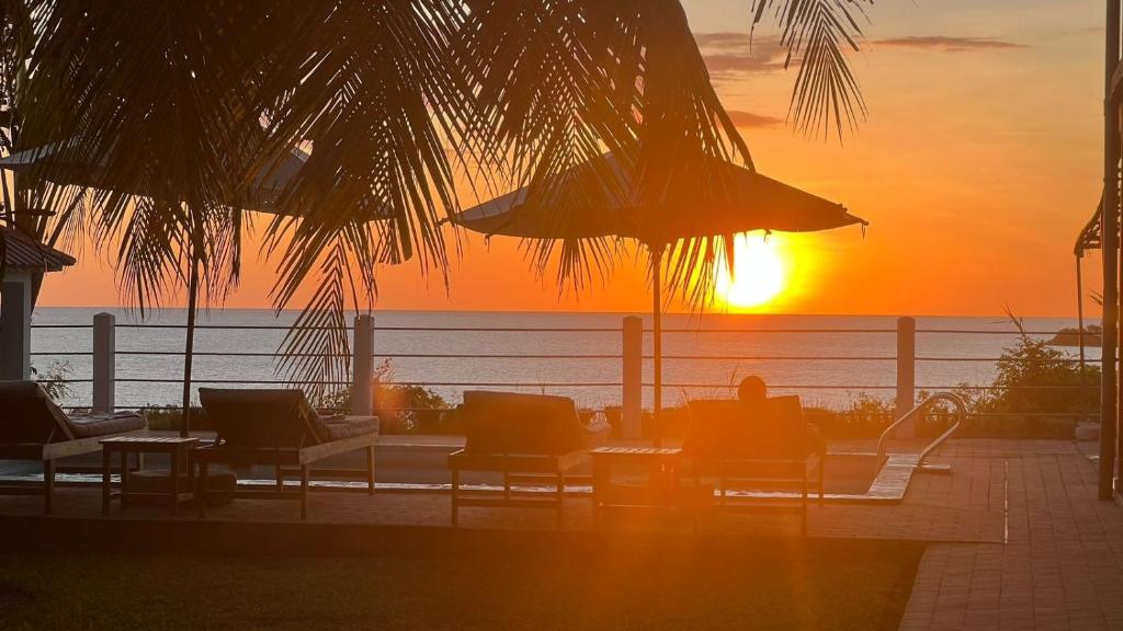 a sunset over the ocean with chairs and tables with the sun setting at Nosy Bay View in Nosy Be