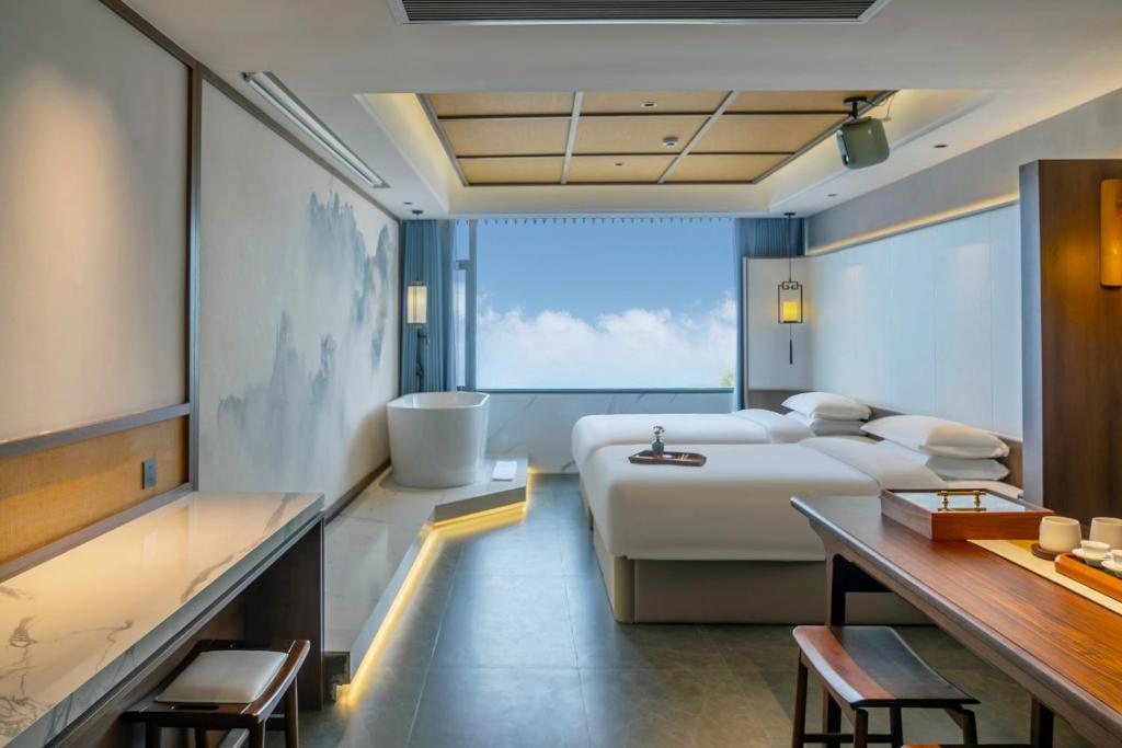 a hotel room with a bed and a bath tub and a bed and a table at Dayucang Tea Sea Cloud Inn Jingmai Ancient Tree Tea Forest Store in Mengzhe