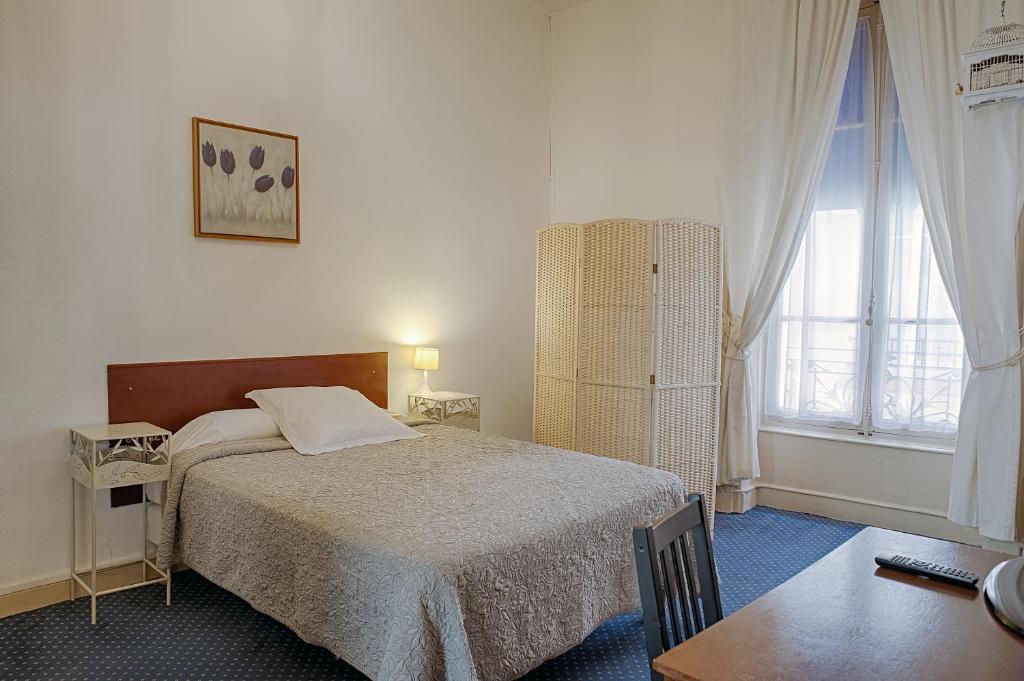 1 dormitorio con cama, mesa y ventana en Hôtel des Facultés, en Lyon