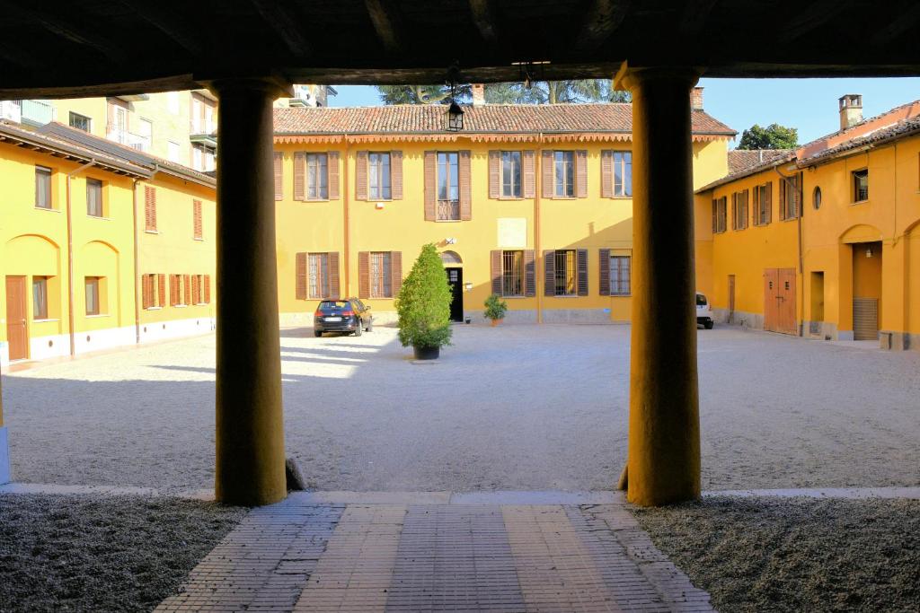 un gran edificio amarillo con columnas en un patio en Corte Certosina en Trezzano sul Naviglio