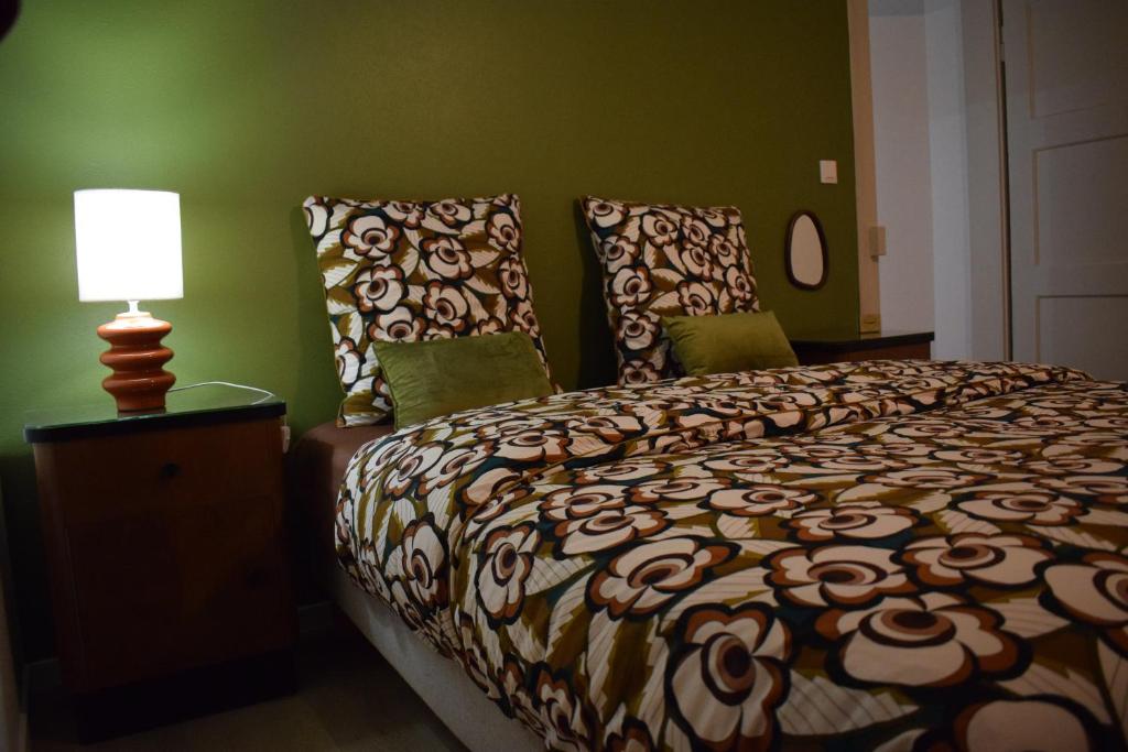une chambre avec un lit, une lampe et des murs verts dans l'établissement Le 70s 2 pièces proche Colmar, à Holtzwihr