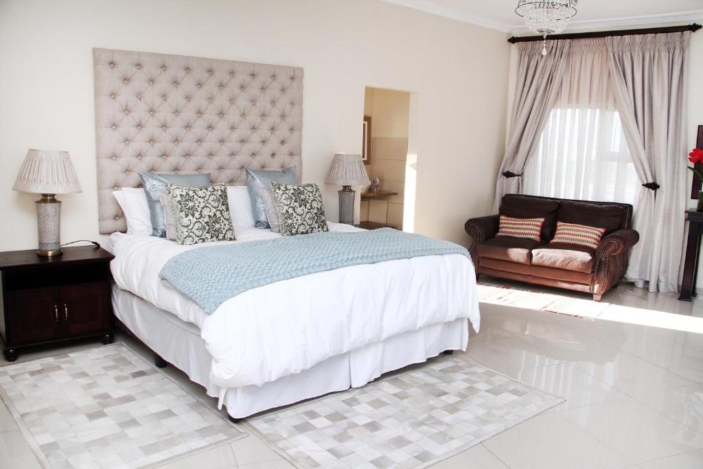 a white bedroom with a large bed and a couch at Black Horses Lodge & Conferencing in Vryheid