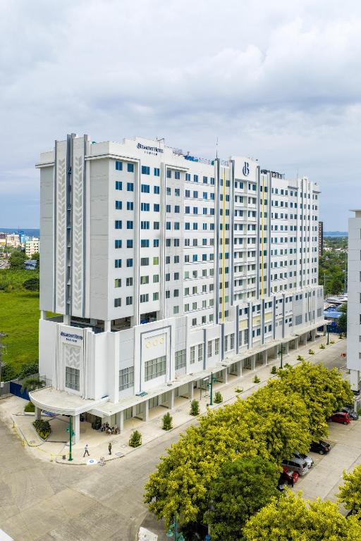 a large white building with trees in front of it at Belmont Hotel Iloilo in Iloilo City