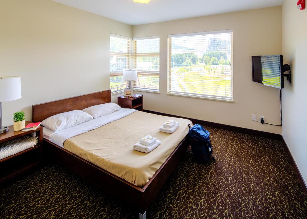 una camera da letto con un letto con due asciugamani sopra di HI Whistler - Hostel a Whistler