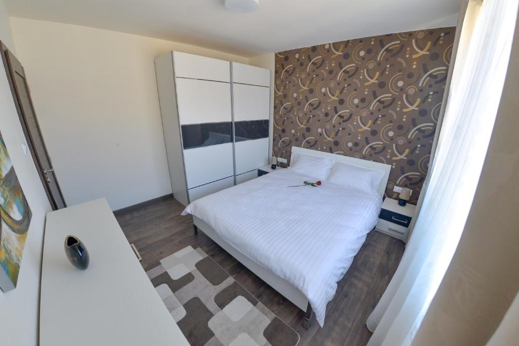 シビウにあるΛηΥα Apartment Sibiuの白いベッドと壁が備わる小さなベッドルーム1室が備わります。