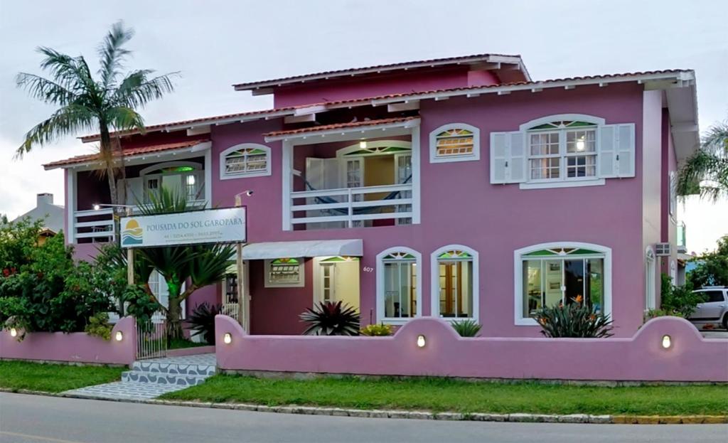 uma casa cor-de-rosa do lado da rua em Pousada Do Sol Garopaba em Garopaba