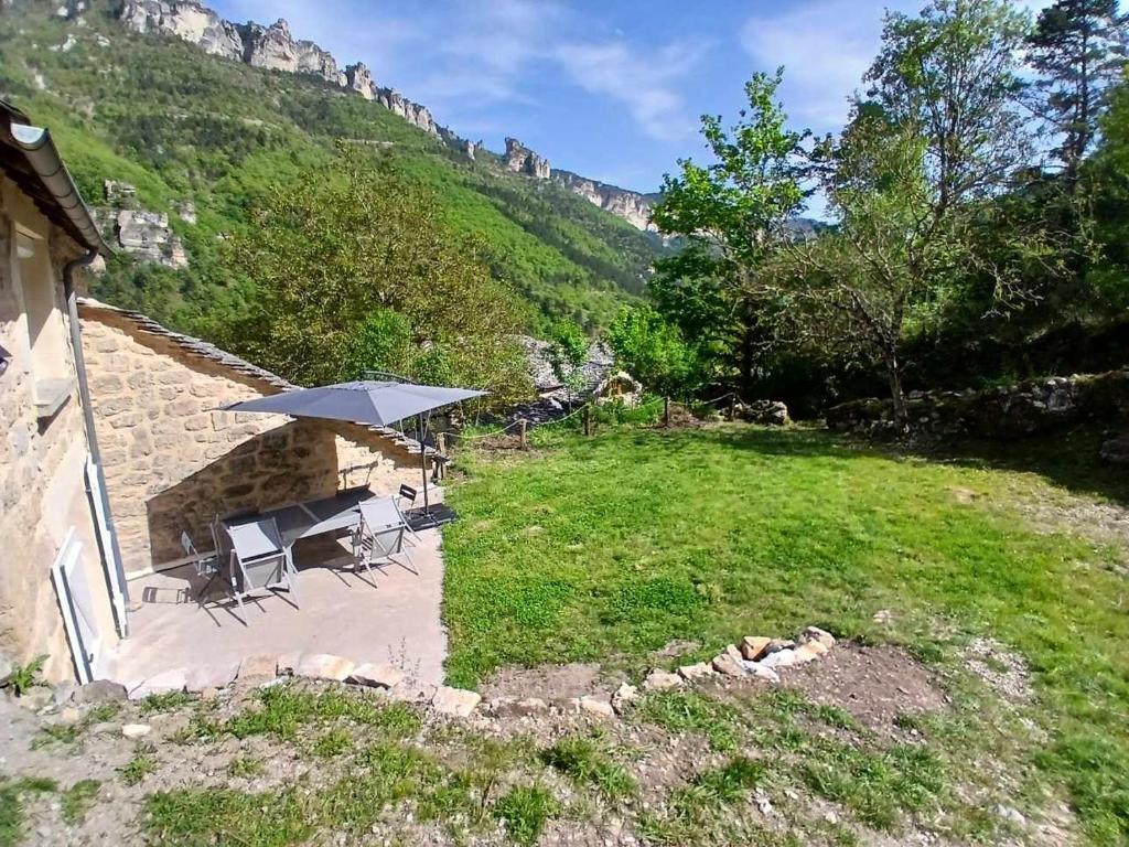 a patio with a table and chairs and an umbrella at Gîte au cœur des Gorges du Tarn in Saint-Rome-de-Dolan
