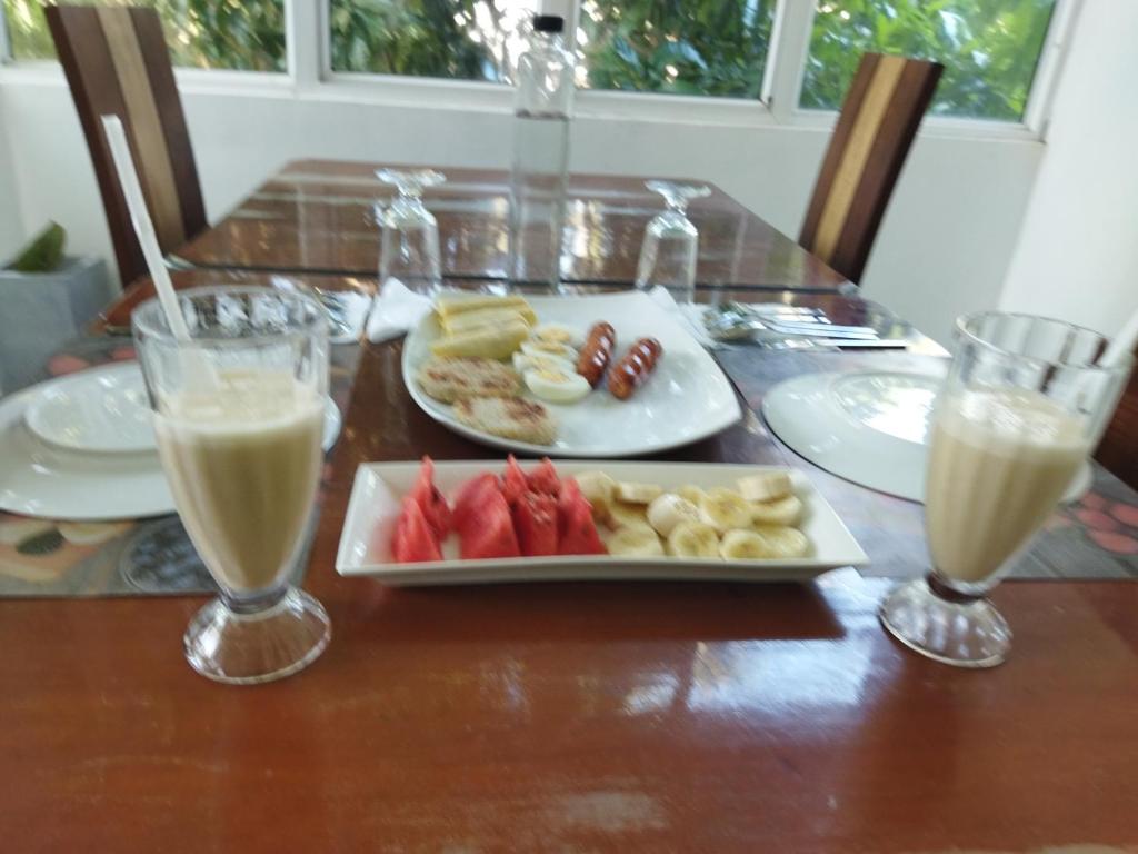 a table with a plate of food and two glasses of milk at Three M Mirissa in Mirissa
