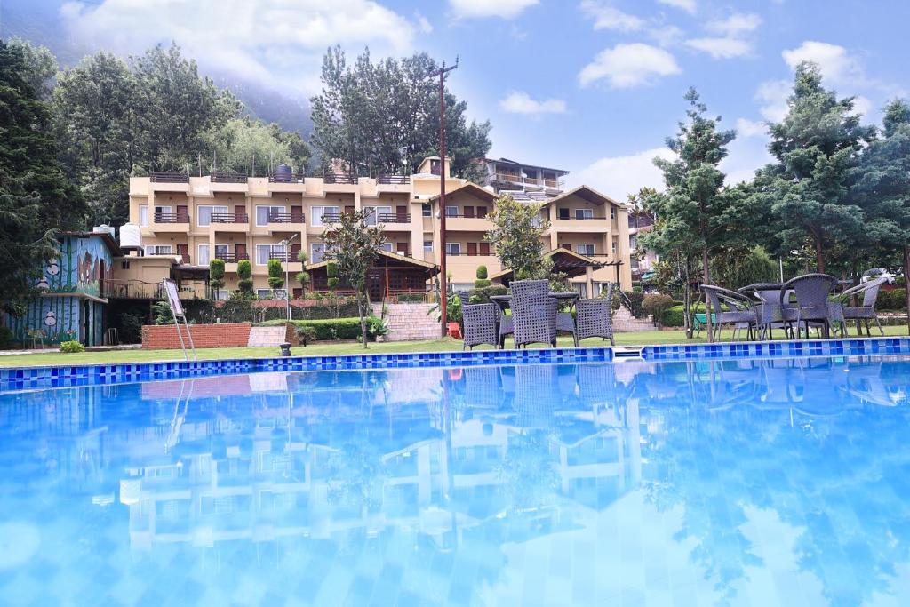 a large swimming pool in front of a hotel at Foxoso Misty Oaks - Hotel & Resort in Bhowāli