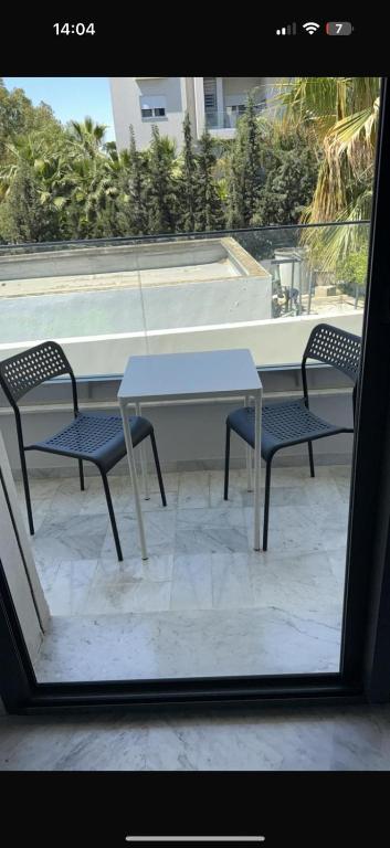 a table and two chairs sitting next to a window at NOUR appartement in Sidi Daoud