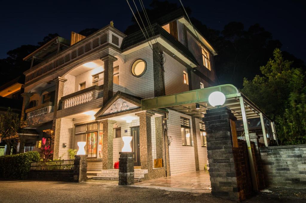 an old house with a lit up sign in front of it at So Art Guesthouse in Sanyi