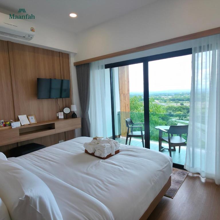 a bedroom with a large white bed and a large window at โรงแรมม่านฟ้า in Ban Na Tho