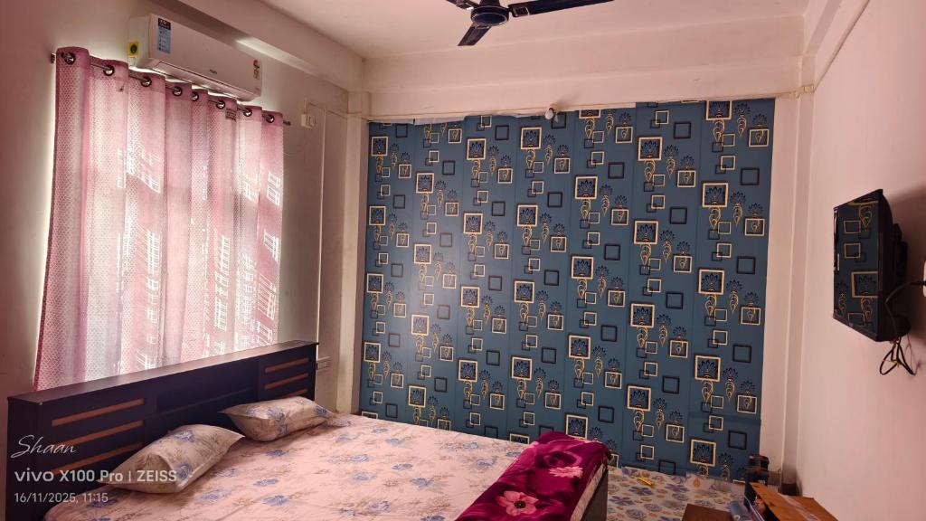 Un dormitorio con una cama y una cortina azul. en Shaan's Homestay, en Jorhat