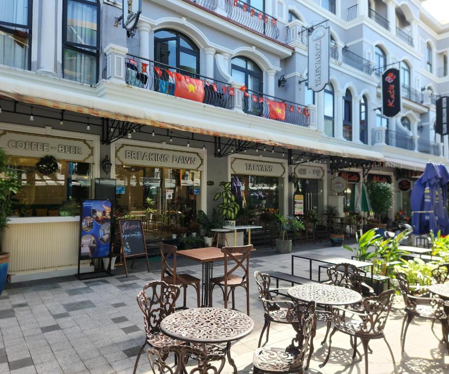 Un patio con mesas y sillas frente a un edificio. en BREAKING DAWN- TAEYANG Hotel Phú Quốc, en Phu Quoc