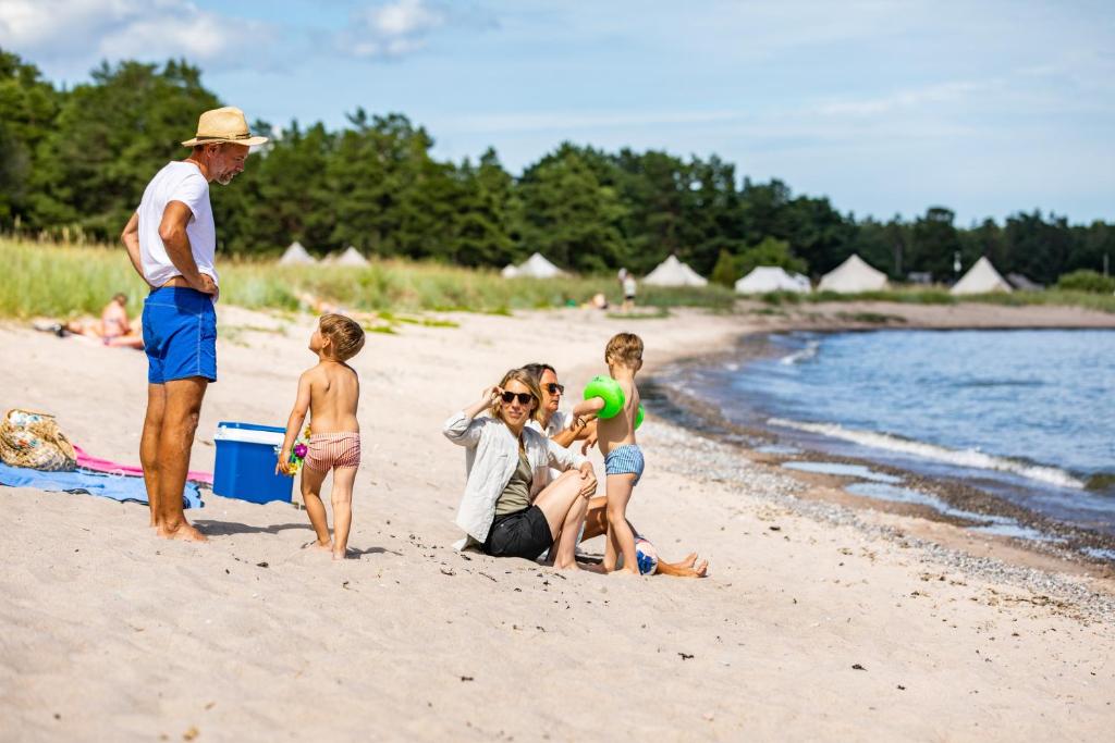 Una mujer y dos niños sentados en una playa en Havsängen Ljugarn, en Ljugarn