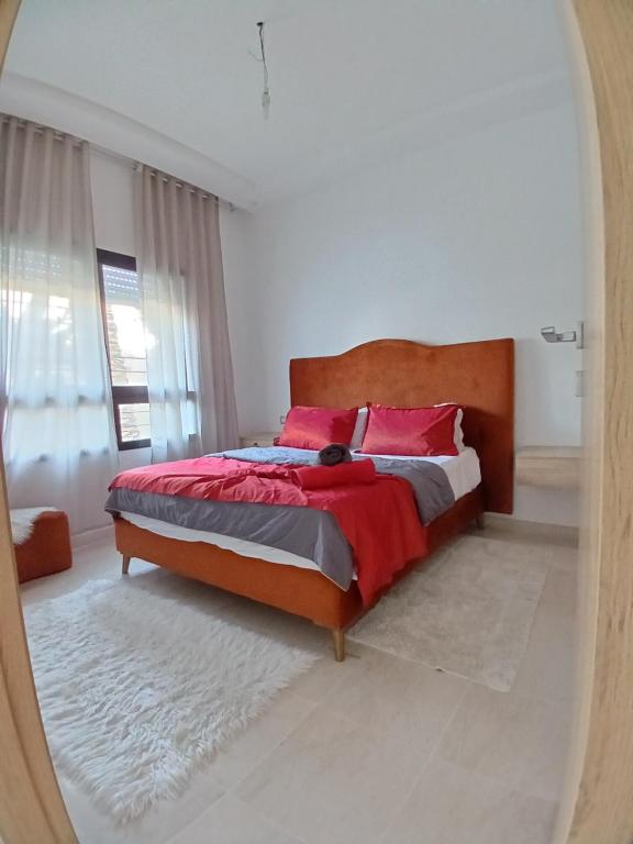 Un dormitorio con una cama con almohadas rojas y un espejo. en Chiraz Magesty loft, en Sidi Daoud