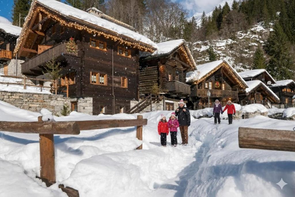 eine Gruppe von Menschen, die im Schnee vor einer Lodge spazieren in der Unterkunft Incanto Walser Apartments Testa in Macugnaga