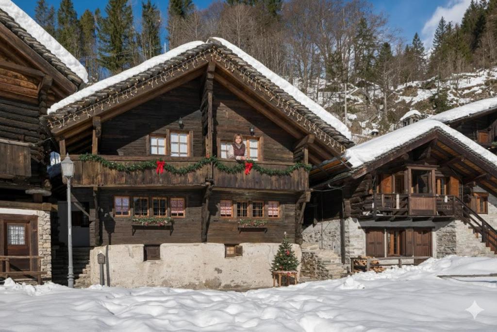 een blokhut met kerstversieringen erop in de sneeuw bij Incanto Walser Apartments Testa in Macugnaga