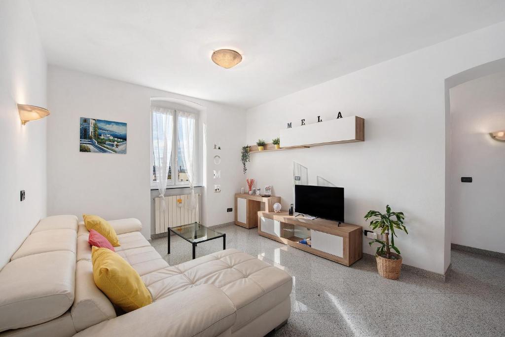 a white living room with a couch and a tv at Mela Garden House in Genova