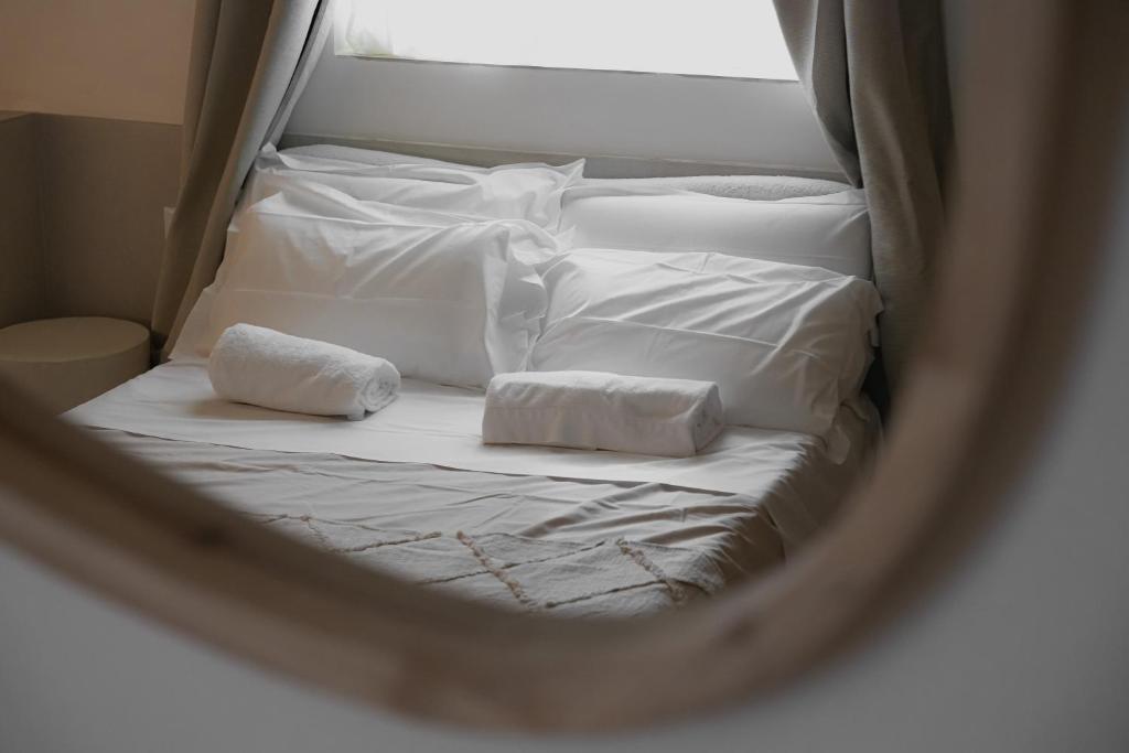 un letto con lenzuola bianche e asciugamani in uno specchio di San Michele Rooms & Private Spa - via Santa Cesarea a Matera