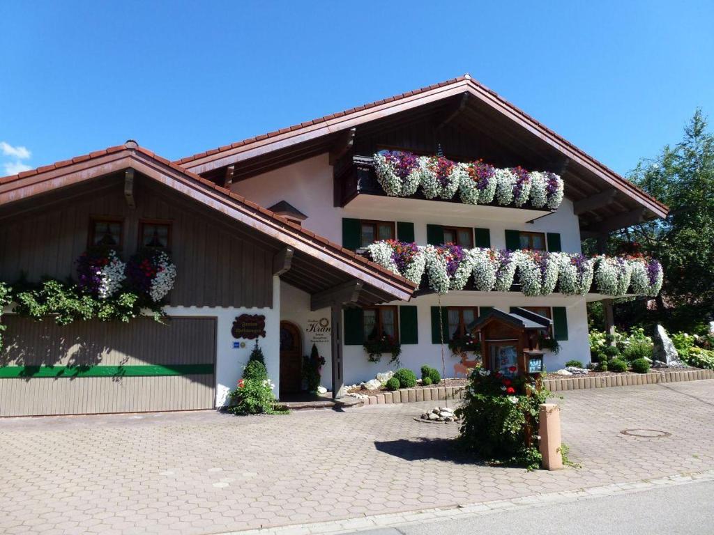 a white building with flower boxes on the roof at Landhaus Kränzle in Fischen