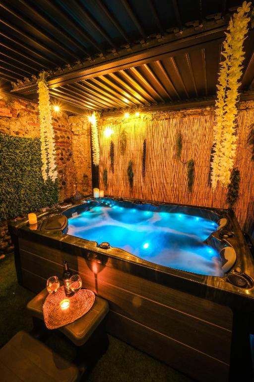 a large jacuzzi tub in a room with lights at La Villa Lova - Loveroom avec spa privatif à Pamiers in Pamiers