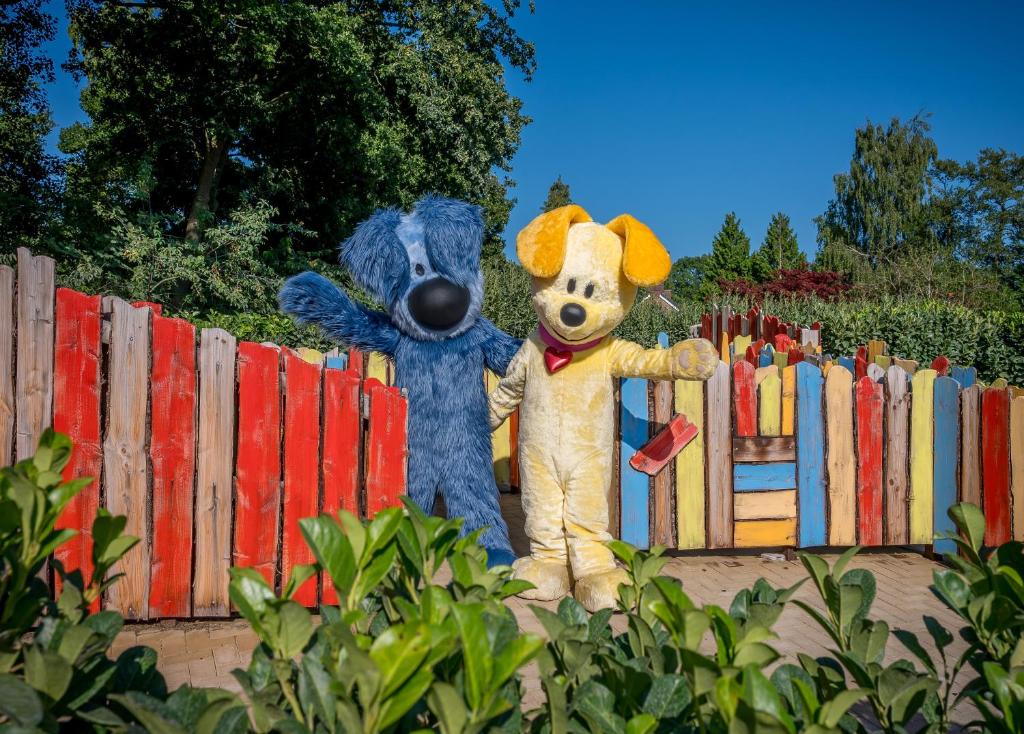 two mascots are standing next to a fence at Familie Resort de Tovertuin in Hoogerheide