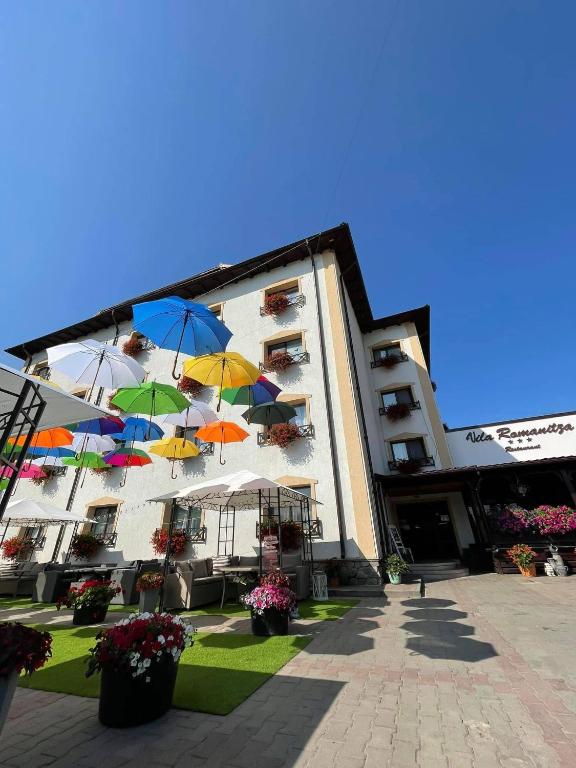 a building with colorful umbrellas in front of it at Vila Romanitza in Dărmăneşti