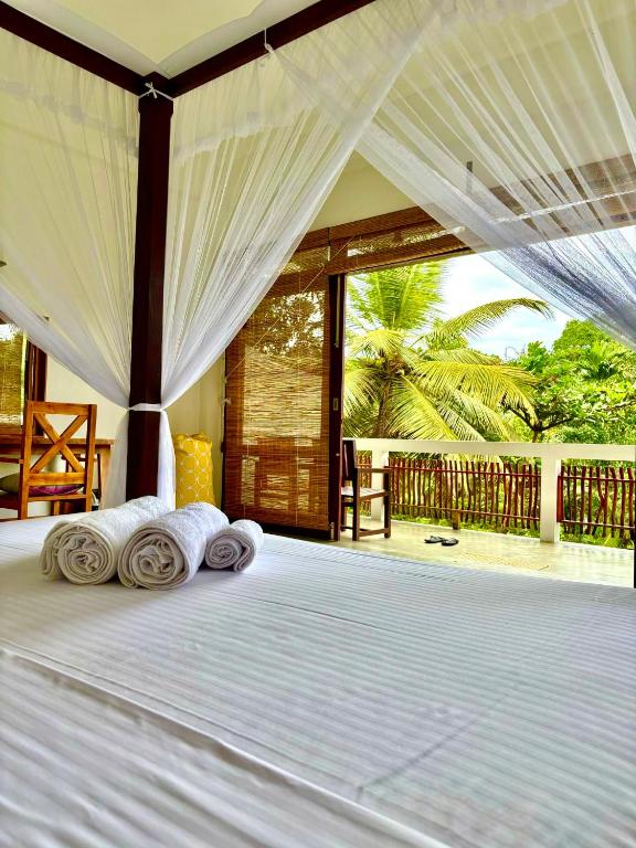 a bedroom with a white bed with a canopy at CoCo-SuRf-House, Luxury among palms in Hikkaduwa