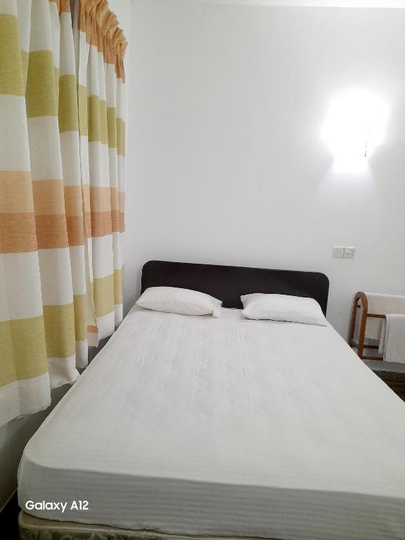a bed in a room with a curtain at Hotel Ameliya in Kandy