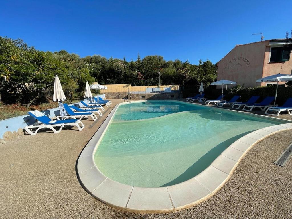 a large swimming pool with lounge chairs and umbrellas at Blu Marlin Apartment in Santa Maria Coghinas