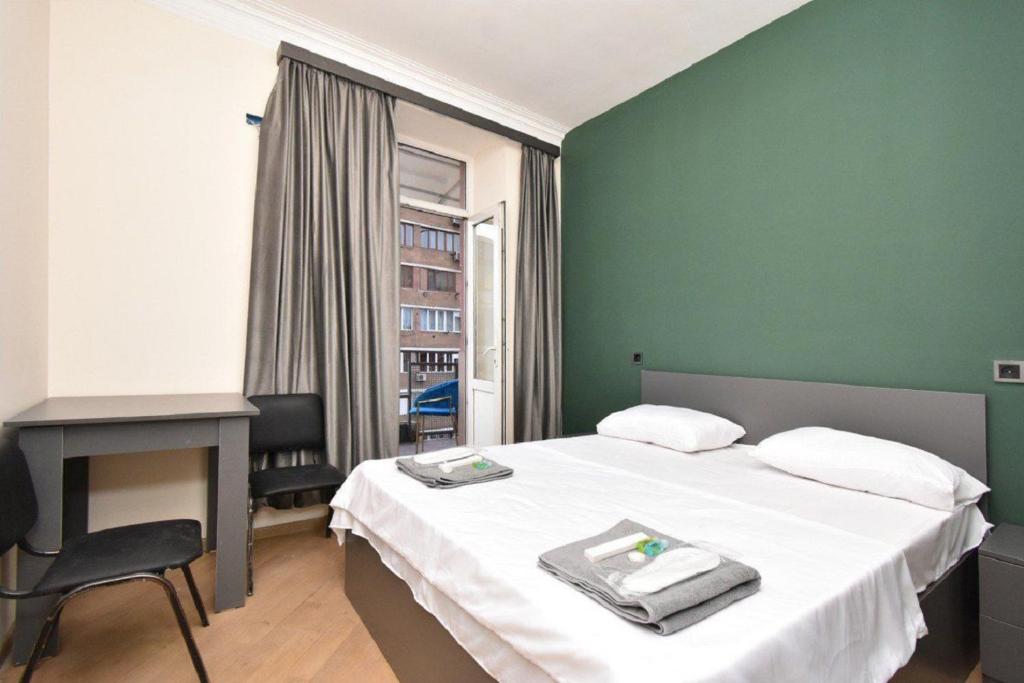 a bedroom with a bed and a desk and a window at tumanyan 38 guest hause in Yerevan