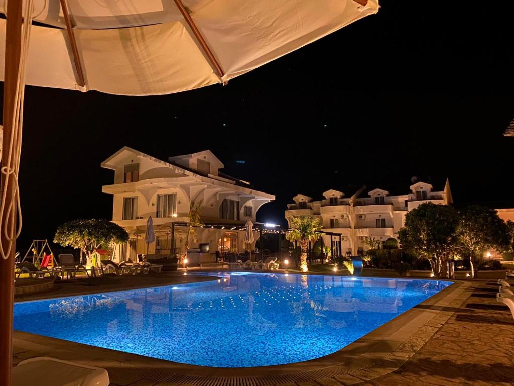 a swimming pool in front of a house at night at Hotel Resort Comfort in Ulcinj
